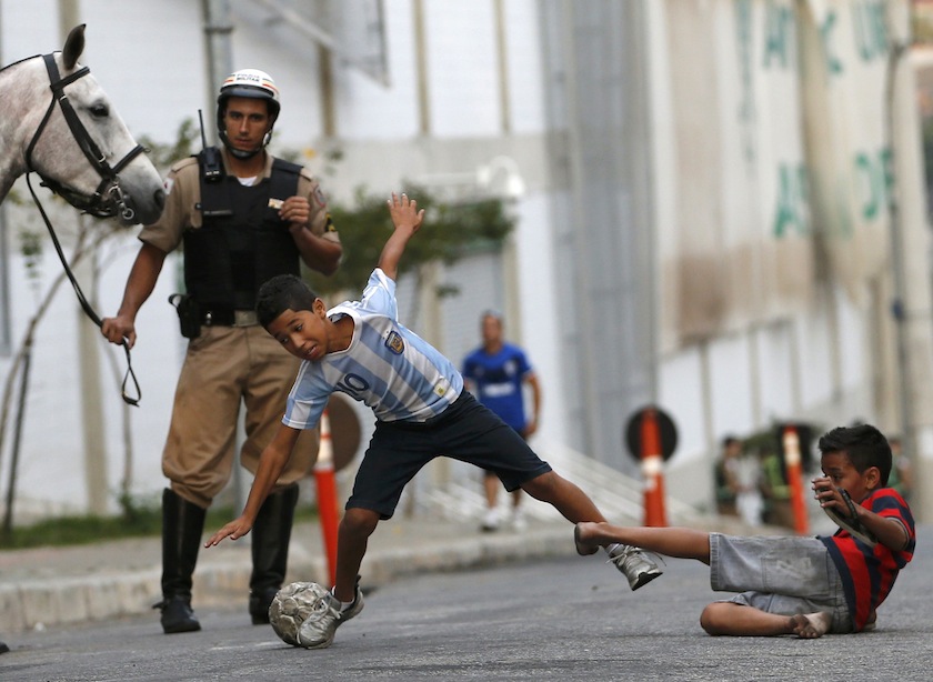 Kids play on a street as a police officer watches outside Independencia stadium before the start of the Argentine national team training session in preparation for 2014 World Cup in Belo Horizonte, June 11, 2014. u00e2u20acu201d Reuters pic