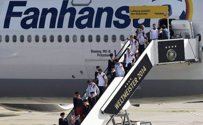 Germany's national football team captain Philipp Lahm (lower centre) holds the World Cup trophy as he leads members of Germany's 2014 Brazil World Cup squad disembark from their plane at Tegel airport in Berlin, July 15, 2014 Reuters