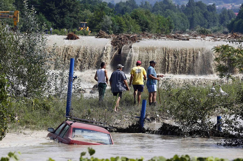 Men pass by a car that is partially submerged in floodwaters in Novaci, southwest Romania, July 30, 2014. u00e2u20acu2022 Reuters pic