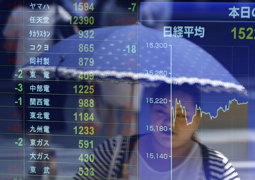 File picture shows a woman holding an umbrella being reflected in an electronic stock quotation board outside a brokerage in Tokyo, July 14, 2014. u00e2u20acu201d Reuters pic