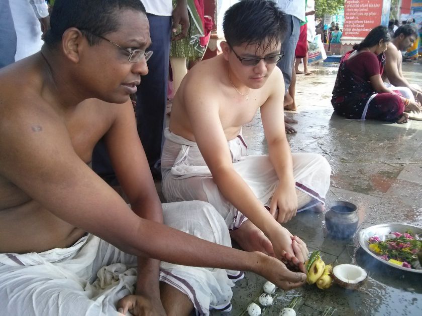 Eddie and I, completing the rituals beside the riverside next to the famous temple. Cows just behind us, waiting for food. — Picture by Praba Ganesan