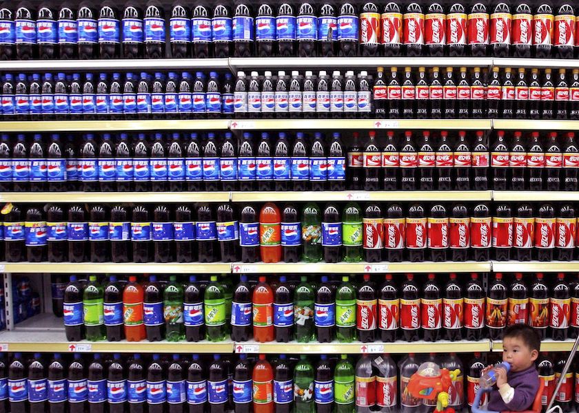 A boy sitting in a toy tricycle is pushed past shelves of bottled beverages at a supermarket in Nanjing, east China's Jiangsu province in this April 10, 2006 file photo. u00e2u20acu201d Reuters pic