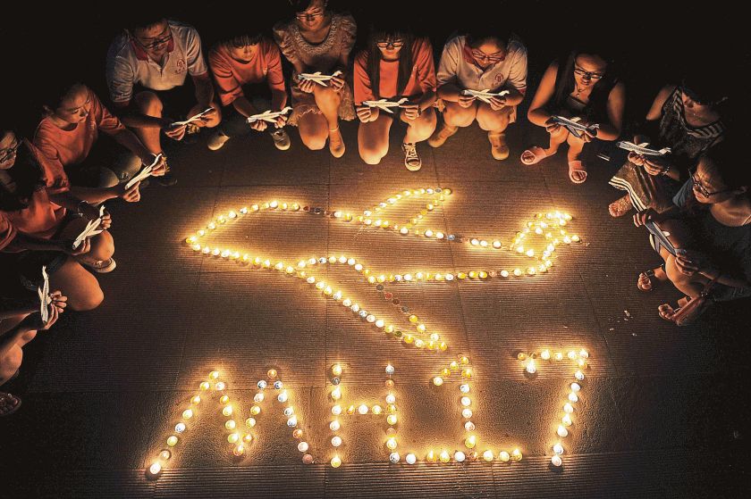 College students gather around candles forming the shape of an airplane, during a candlelight vigil for victims of the downed Malaysia Airlines Flight MH17, at a university in Yangzhou, Jiangsu province July 19, 2014. — Picture by Reuters