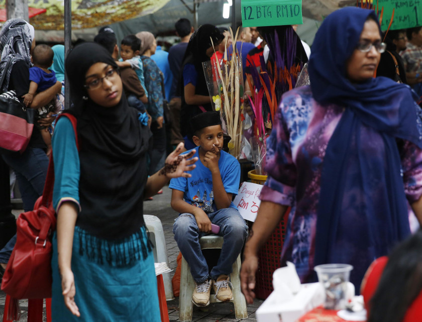 Women shop before Hari Raya Aidilfitri celebrations, which marks the end of Ramadan, as a boy looks on in Kuala Lumpur July 27, 2014. u00e2u20acu201d Reuters pic