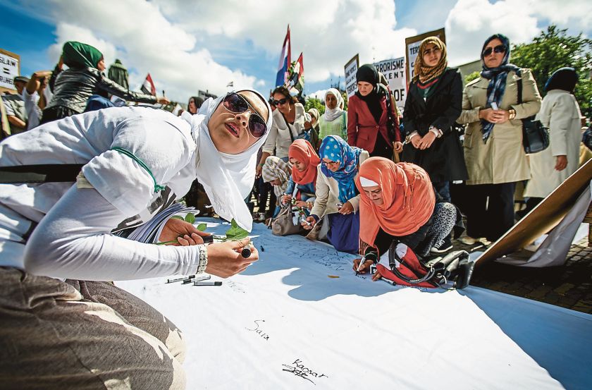 Muslim women sign a banner during a demonstration against the violent uprising of IS in the centre of The Hague, June 29, 2014. Banners read ‘Terrorism does not believe in religion’ and ‘One voice against terrorism’. — Picture by AFP