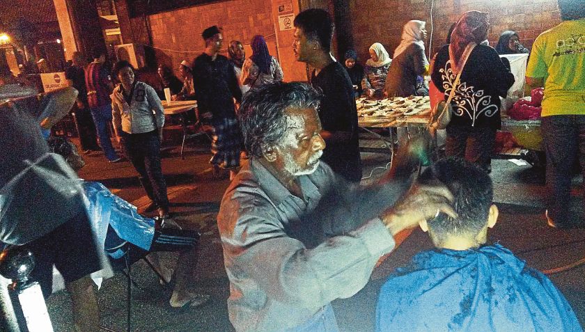 Volunteers give haircuts to the homeless in the Masjid Jamek area. u00e2u20acu201d Picture by Zuraneeza Zulkifli