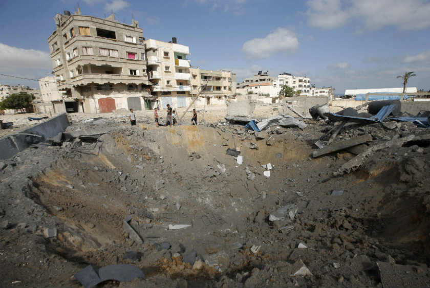 Palestinians stand next to a crater which police said was caused by an Israeli air strike in Gaza City July 3, 2014. u00e2u20acu201d Reuters pic