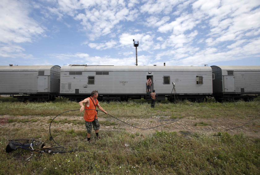 Railway employees are pictured as they work near refrigerator wagons, which according to employees and local residents contain bodies of passengers of the crashed MH17, at a railway station in Torez, July 20, 2014.