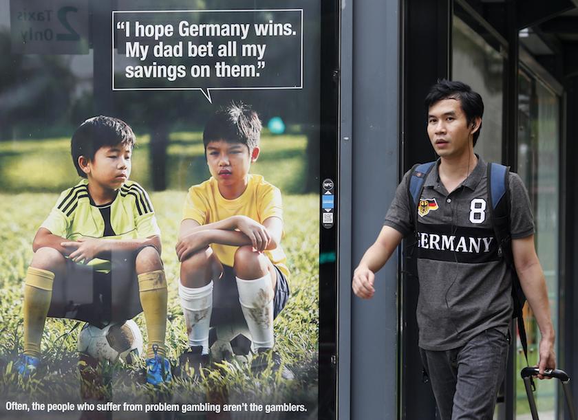 A man walks past a World Cup anti-gambling advertisement at a taxi stand in Singapore in this July 9, 2014 file photo. u00e2u20acu201d Reuters pic