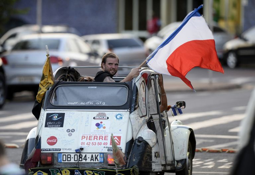 A French fan proudly waves the country's flag from the back seat of a classic Citroen 2CV car. u00e2u20acu201d AFP pic
