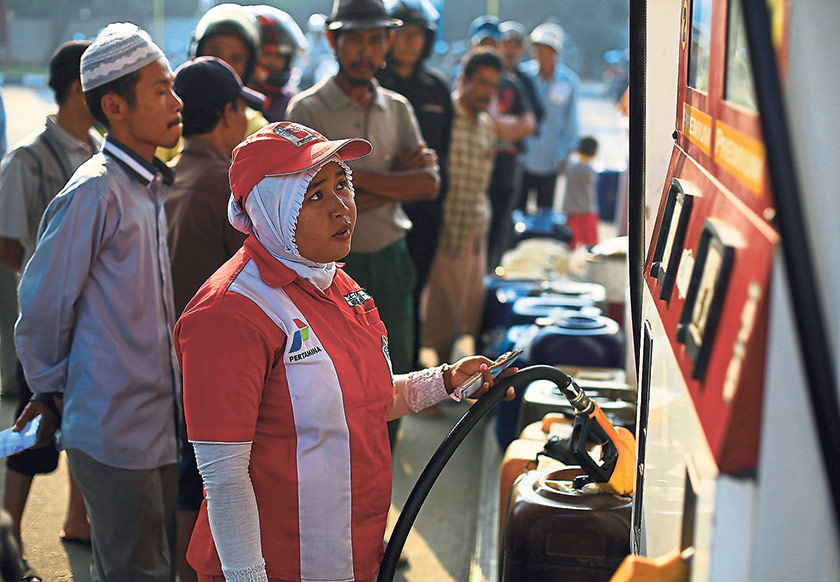 A PT Pertamina fuel station worker fills a container with subsidised fuel, as people wait in a line at the Mauk district fuel station in Tangerang, Banten province August 27, 2014. — Reuters pic