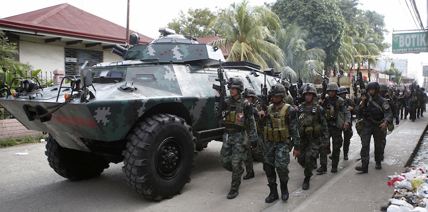 Members of the elite Special Action Police walk next to an armoured vehicle as they reinforce soldiers battling Muslim rebels from the Moro National Liberation Front in Zamboanga city, in southern Philippines in this September 12, 2013 file photo. u00e2u20acu201d Reu