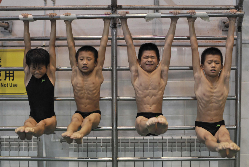 Young divers stretch as they hang from a steel bar during a training session at a sports school in Hefei, Anhui province August 23, 2014. u00e2u20acu201d Reuters pic