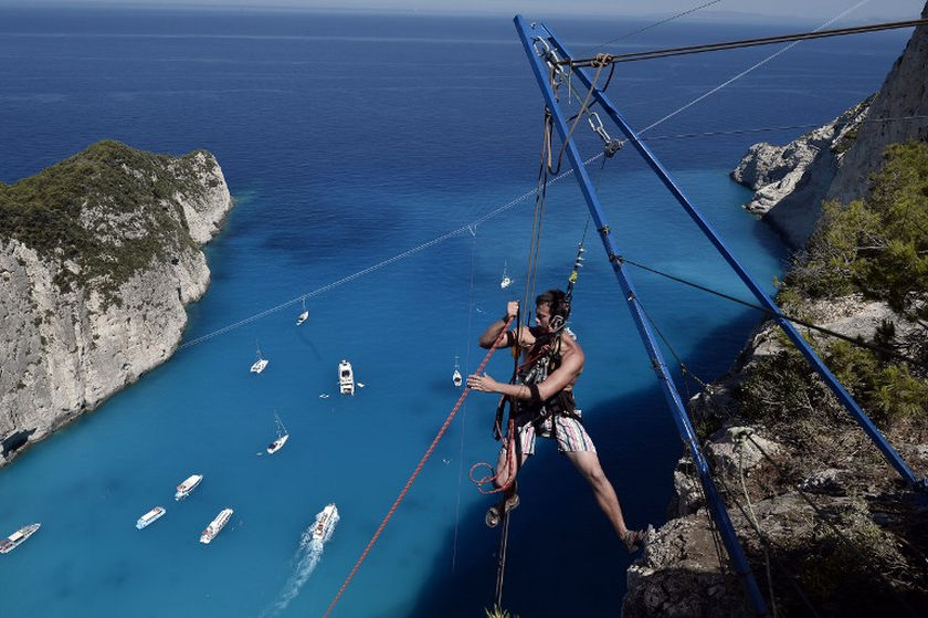 A member of the 'dream walker' team climbing up after jumping from atop the rugged rocks overlooking the azure waters of Navagio beach, on Greece's Zakynthos island June 23, 2014. — AFP pic