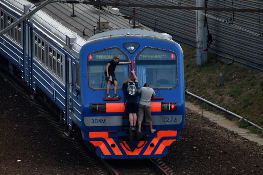 Men cling on a local train end near the Losinoostrovskaya station in a suburb of Moscow on July 25, 2014. u00e2u20acu201d AFP pic
