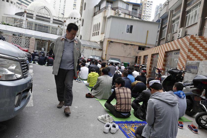 File picture shows a Han Chinese man looking at Uighur people as they pray at a mosque in Shanghai, April 11, 2014. u00e2u20acu201d Reuters pic