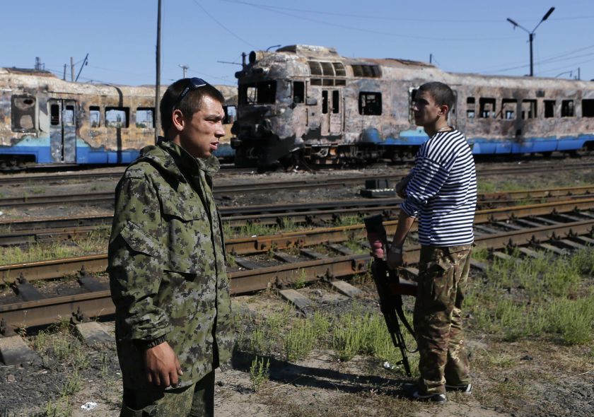 Pro-Russian separatists stand in front of destroyed trains at a railway station in the eastern Ukrainian town of Ilovaysk, August 31, 2014.