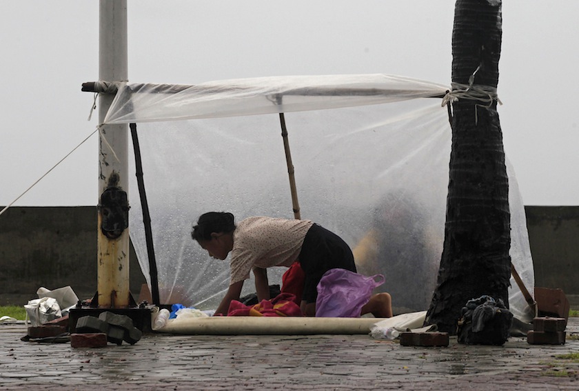 A woman shields herself with a plastic sheet from the rain brought on by Typhoon Kalmaegi, also called Luis, on the street at a bay in Manila September 14, 2014.u00c2u00a0u00e2u20acu201d Reuters pic