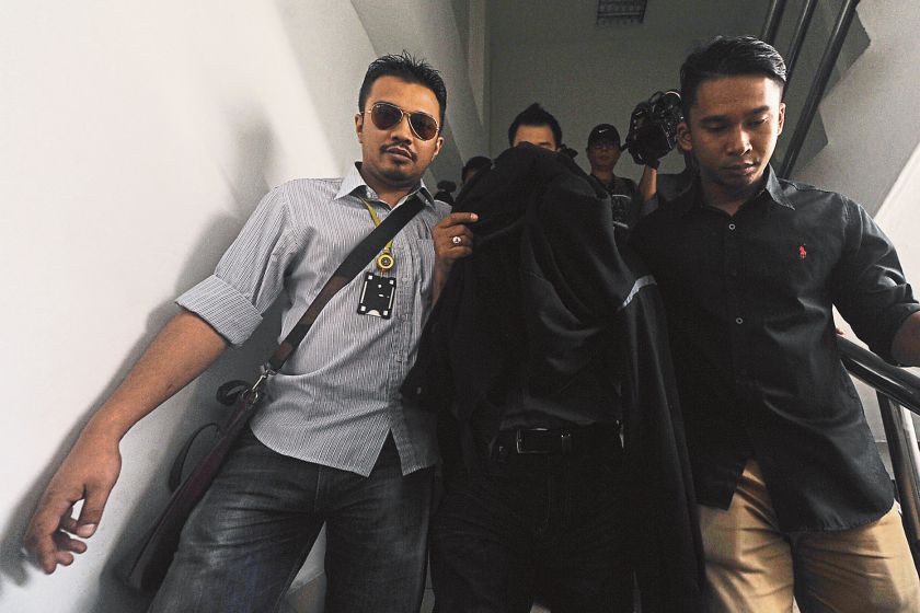 Customs officers escort one of the suspects after he was charged with corruption at the KL Courts in Jalan Duta on Friday. — Picture by Azinuddin Ghazali