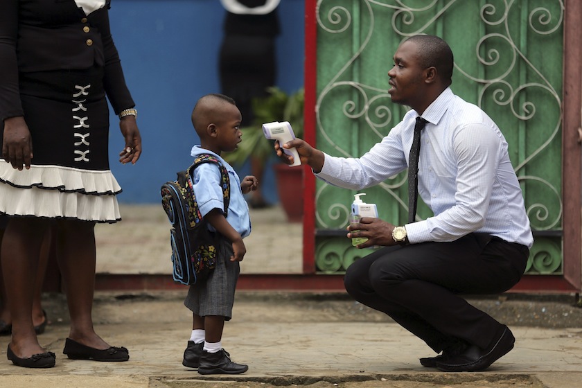 A school official takes a pupil's temperature using an infrared digital laser thermometer in front of the school premises, at the resumption of private schools, in Lagos September 22, 2014. u00e2u20acu201du00c2u00a0Reuters pic
