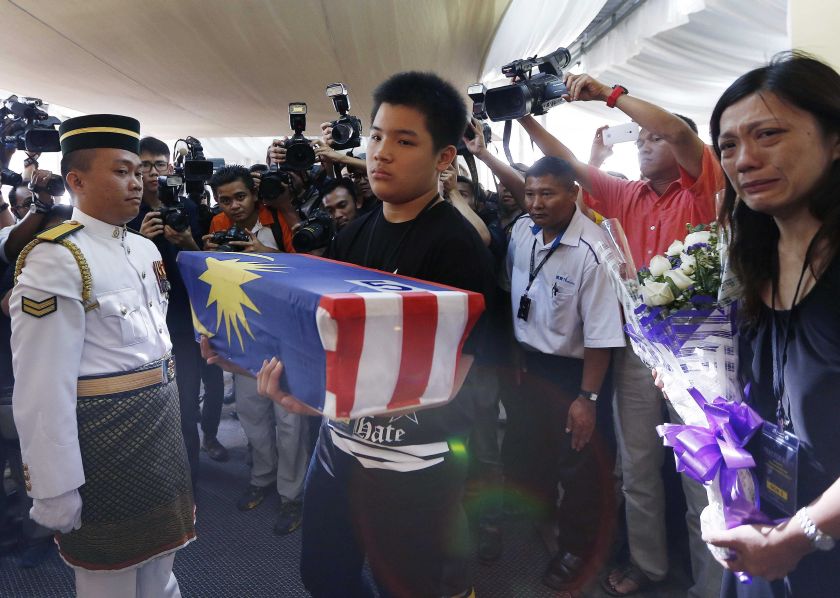Melvic Choo, 13, carries the ashes of his father MH17 co-pilot Eugene Choo, while standing near his mother Ivy Loi (left) at the wake in Seremban September 2, 2014. u00e2u20acu2022 Reuters pic