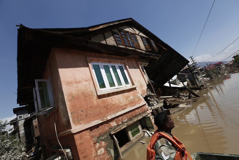 An Indian army soldier sits in a rescue boat past a destroyed house as he and others search for stranded flood victims in Srinagar September 13, 2014.u00c2u00a0u00e2u20acu201d Reuters pic