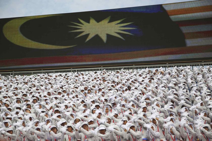 Performers stand in front of a large screen showing the national flag during Independence Day, or Merdeka Day, celebrations in Kuala Lumpur August 31, 2014. u00e2u20acu2022 Reuters pic