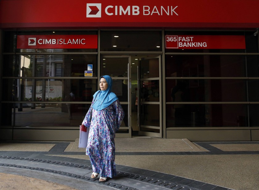  woman leaves a CIMB bank branch in Putrajaya in a file picture. CIMB Group, RHB Capital Bhd and Malaysia Building Society Bhd (MBSB) have agreed on a merger deal that will create the country's biggest banking group. u00e2u20acu201d Reuters pic