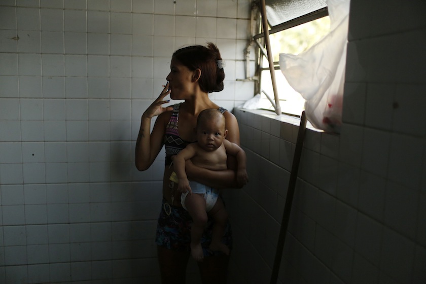 A woman holding her baby smokes a cigarette as she waits for a washing machine, before doing laundry inside the bathroom at the Nova Tuffy slum, in an abandoned factory in Rio de Janeiro October 17, 2014. u00e2u20acu201d Reuters pic