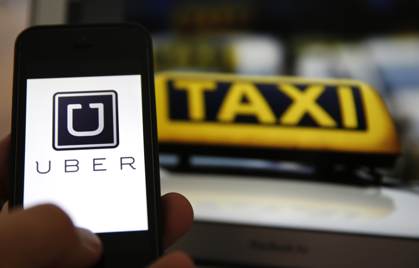 An illustration picture shows the logo of car-sharing service app Uber on a smartphone next to the picture of an official German taxi sign in Frankfurt, September 15, 2014. u00e2u20acu201d Reuters pic