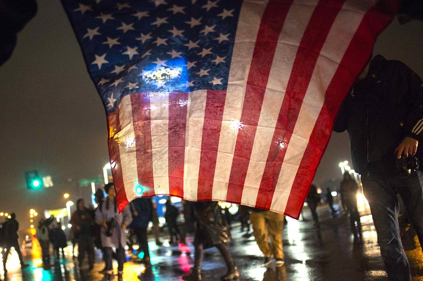 Protesters, demanding the criminal indictment of a white police officer who shot dead an unarmed black teenager in August, hold a US flag while marching through a suburb in St. Louis, Missouri November 24, 2014. u00e2u20acu201d Reuters pic