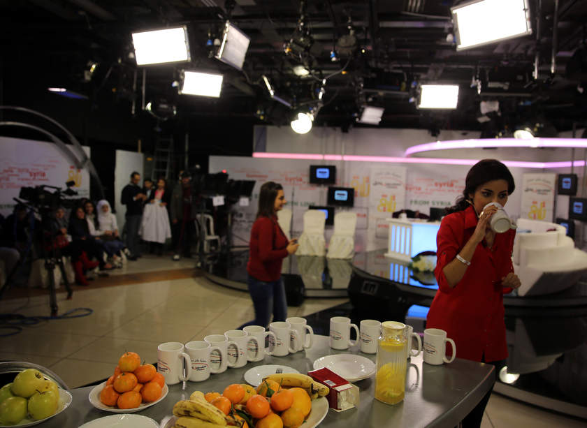 TV host Areej Zayat (right) of the programme 'From Syria with Love' drinks from a mug ahead of taping at Talaqi TV station offices in Damascus, on November 20, 2014. u00e2u20acu201d AFP pic