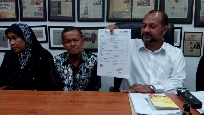 Lawyer Gobind Singh Deo (right) holds up a copy of Syed Mohd Azlanu00e2u20acu2122s autopsy report while accompanying the victimu00e2u20acu2122s parents, Sharifah Halilah Syed Sylaiman, 57, and Syed Muhamad Nur Ali, 67, at a news conference at the formeru00e2u20acu2122s office in Kuala Lumpu
