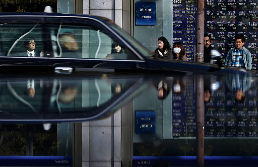 People in front of an electronic board, showing various stock prices, outside a brokerage in Tokyo, November 19, 2014. u00e2u20acu201d Reuters pic