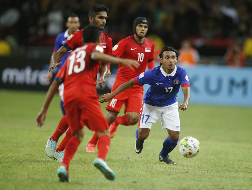Malaysiau00e2u20acu2122s Mohd Amri Bin Yahyah looks to pass against Singaporeu00e2u20acu2122s Ismadi Bin Muhamad Mukhtar (13) and Fazrul Nawaz Shaul Hameed (10) during their Suzuki Cup Group B match in Singapore November 29, 2014. u00e2u20acu201d Reuters pic