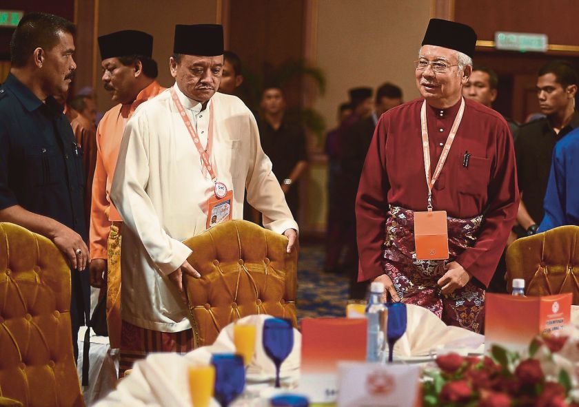 Sukhidir Kemat (in white) pulls a chair for Prime Minister Datuk Seri Najib Razak during the Umno General Assembly yesterday. He has served three prime ministers during events at PWTC in his 29 years as a butler. u00e2u20acu201d Picture by Razak Ghazal
