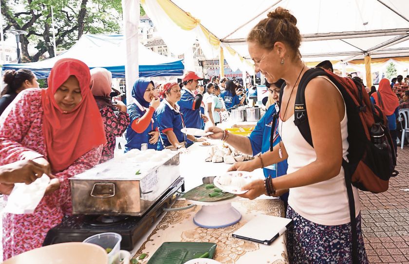 A tourist tries out the local food at the 1Malaysia Peopleu00e2u20acu2122s Breakfast event yesterday. u00e2u20acu201d Picture by Ahmad Zamzahuri