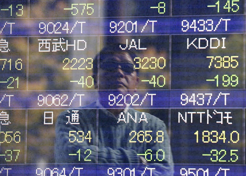 A man is reflected on an electronic stock quotation board outside a brokerage in Tokyo. u00e2u20acu201d Reuters pic