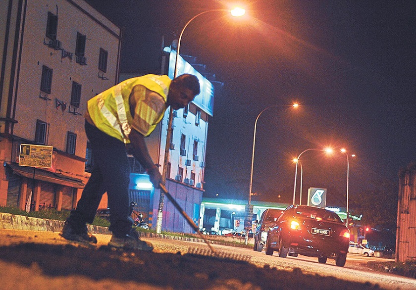 A volunteer patches up a pothole following months of inaction by City Hall. — Picture by Malay Mail