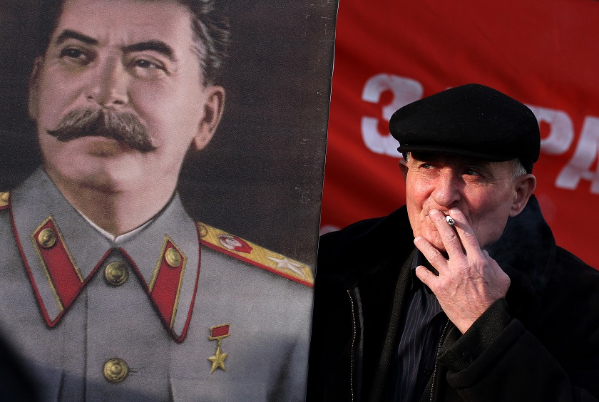 A member of the Belarus Communist Party holds a portrait of Soviet dictator Josef Stalin (left) on November 7, 2014 in Minsk. u00e2u20acu201d AFP pic