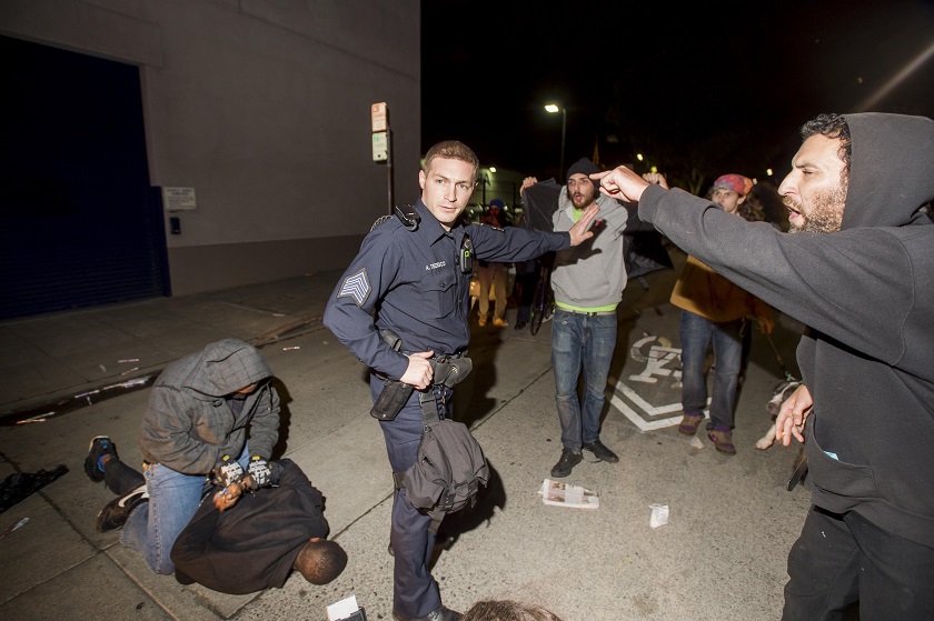 A police officer holds back anti-police demonstrators as an undercover officer makes an arrest in Oakland, California December 10, 2014. u00e2u20acu201d Reuters pic