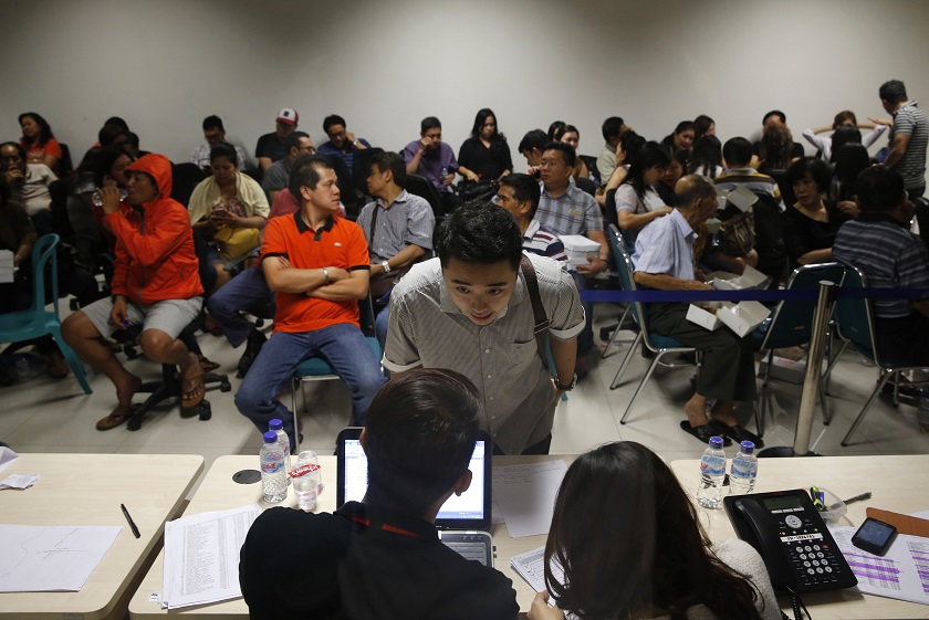 A man (centre) asks an officer for information about his family member who was onboard AirAsia flight QZ8501 at a waiting area in Surabayau00e2u20acu02dcs Juanda International Airport December 28, 2014. u00e2u20acu201d Reuters pic