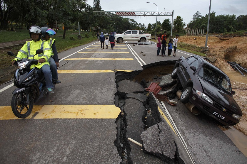 People ride past a road damaged by flooding at Kuala Krai in Kelantan December 30, 2014. u00e2u20acu201d Reuters pic