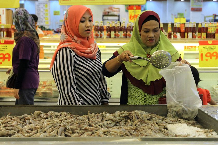Two women are seen buying prawns as water levels in Kelantan begin to recede.