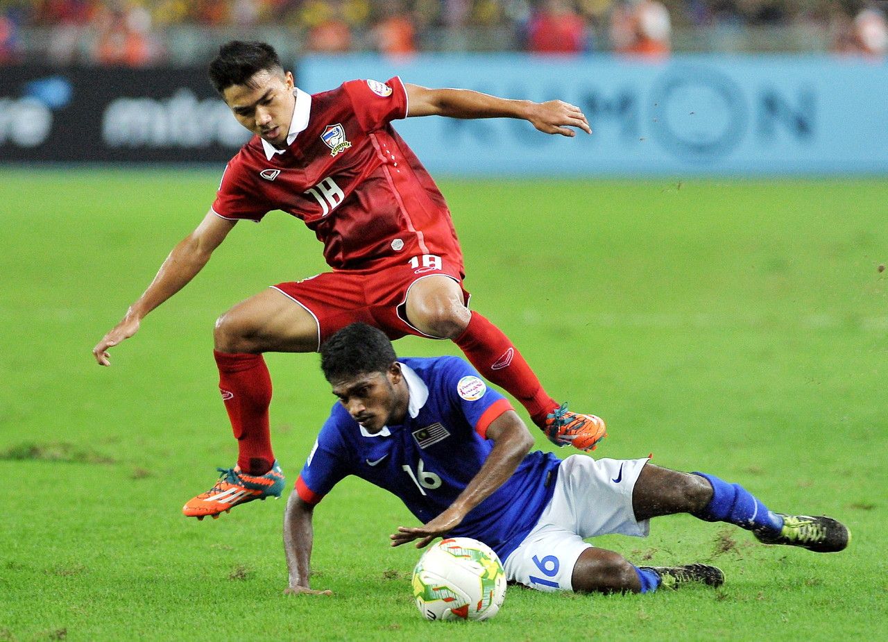 Thailandu00e2u20acu2122s, Chanatip Songkrasin (in red) challenges Malaysiau00e2u20acu2122s, S.Kunalan during their Suzuki Cup final football match at Bukit Jalil Stadium, Kuala Lumpur, December 20, 2014. u00e2u20acu2022 Bernama pic