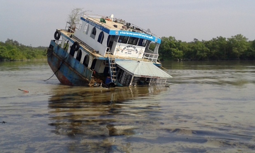 In this photograph taken on December 9, 2014, a Bangladeshi oil-tanker lies half-submerged after it was hit by a cargo vessel on the Shela River in the Sundarbans in Mongla. u00e2u20acu201d AFP pic