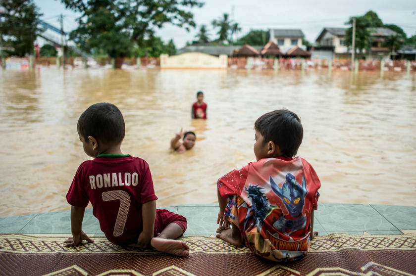 Two boys look on as their friends play in floodwaters in Pengkalan Chepa, near Kota Baru in a picture released December 28, 2014. u00e2u20acu201d AFP pic