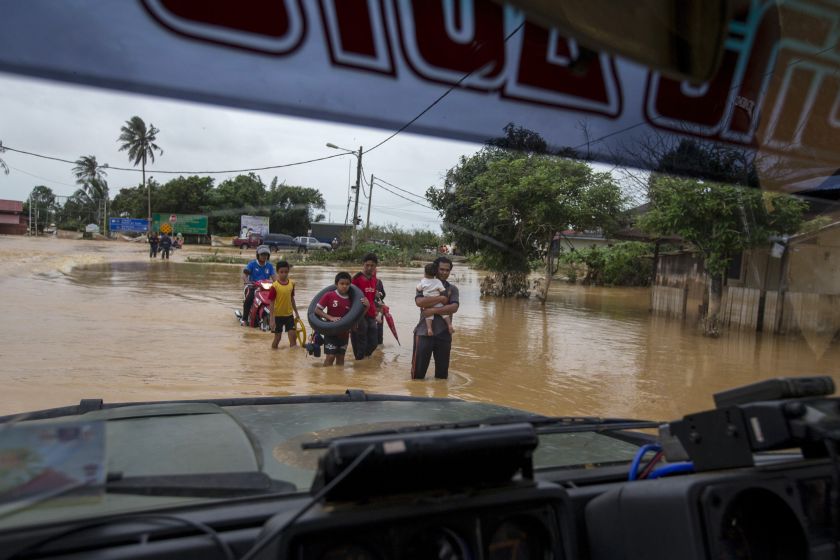 People carry their belongings as they evacuate through a flooded street on the outskirt of Kota Bharu in Kelantan December 30, 2014. u00e2u20acu201d Reuters pic