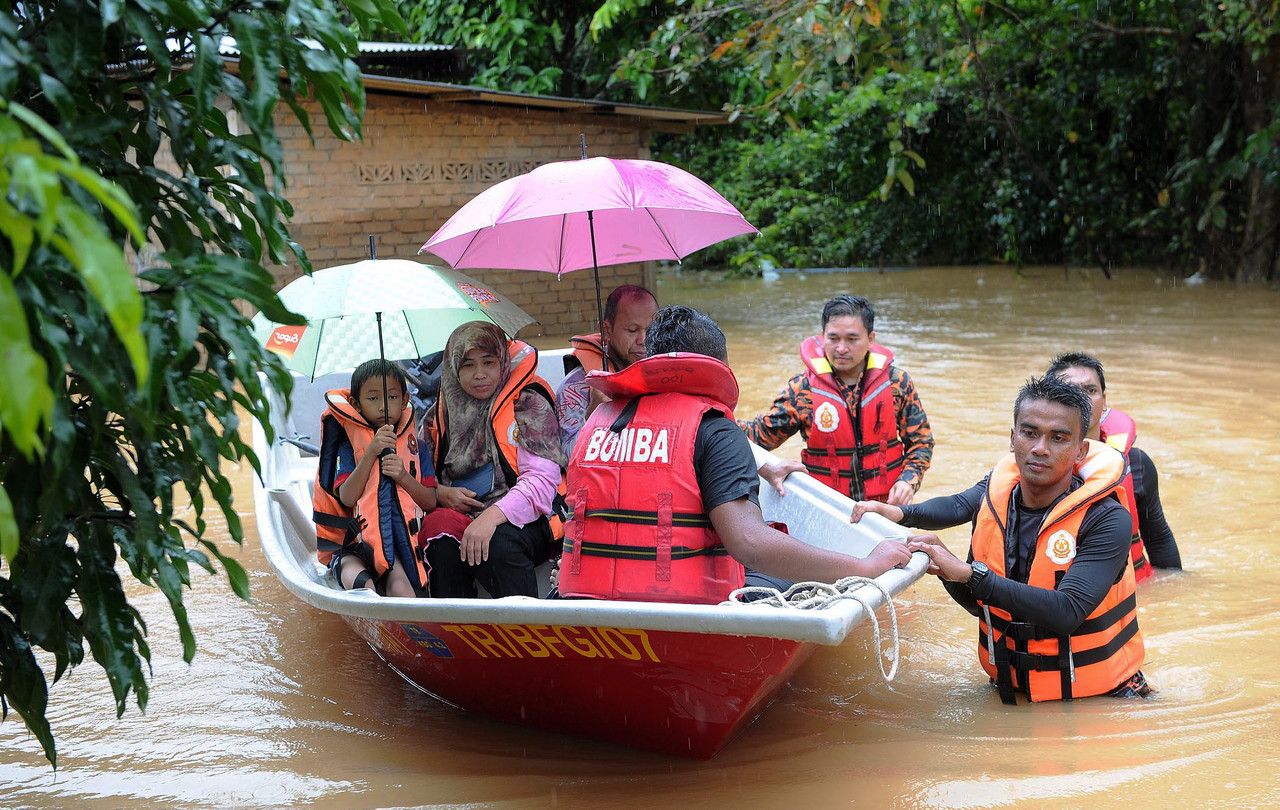 Fire and Rescue Department personnel help steer transfer a family affected by the floods in Kampung Bukit Tadok, to a nearby shelter in Hulu Terengganu, December 20, 2014. u00e2u20acu2022 Bernama pic
