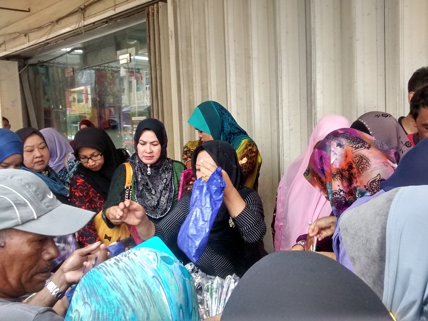 Several elderly women sell cloth for hijabs at cheaply discounted rates, which was aimed at offsetting possible repair costs incurred by the flood at Jalan Temenggong, December 30, 2014. — Picture by Syed Jaymal Zahiid  